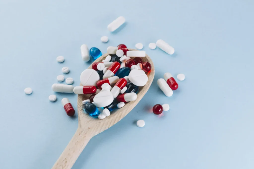 Assorted Pills And Capsules In Wooden Spoon